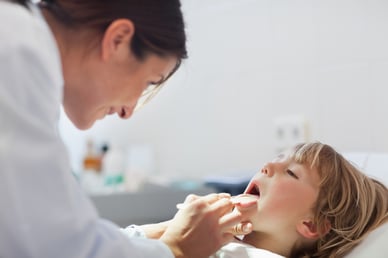 Doctor auscultating the mouth of a child in an examination room