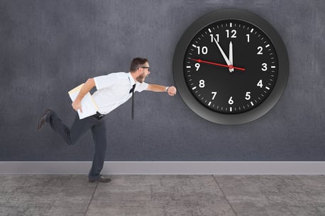 Geeky young businessman running late against grey room