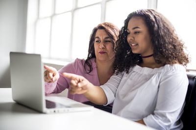 Woman and female student pointing at laptop