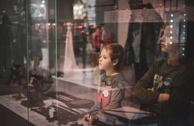 young children stand in front of a glass case at a museum