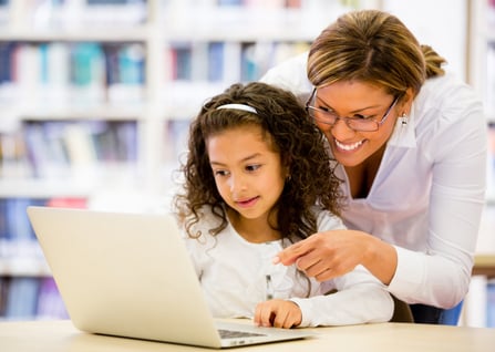 Schoolgirl researching online with the guidance of her teacher